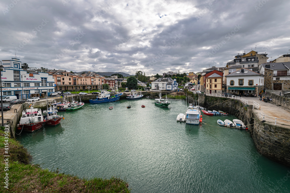 Port area of Puerto de Vega town in Asturias, Spain with beautiful blue waters and fishing boats.