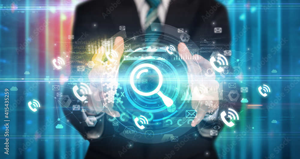 Businessman holding magnifying glass icon in his hands with multiple technology symbols around it