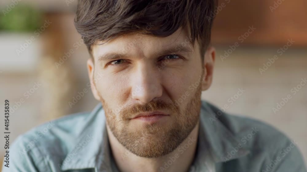 Head and shoulders closeup portrait of confident and determined young man with beard looking at camera Head and shoulders closeup portrait of confident and determined young man with beard looking at camera