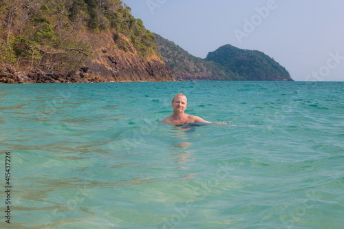 an adult man swims in the sea against the backdrop of mountains in Thailand, on the island of Koh Chang. Summer vacation at sea, travel and tourism © Natalia