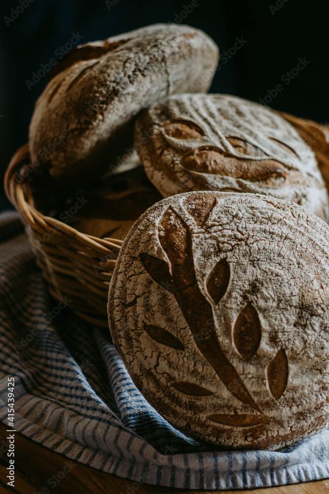 Traditional handmade, homemade sourdough bread in the basket, wooden background, blue teatowel