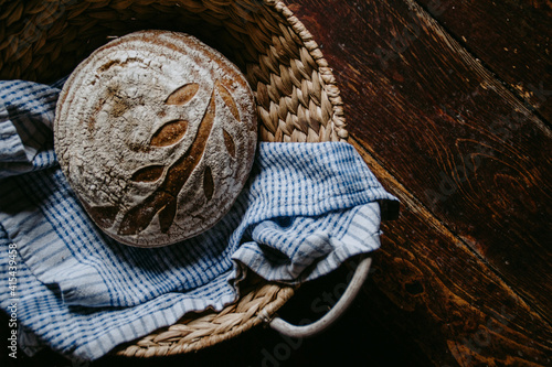 Traditional handmade, homemade sourdough bread in the basket, wooden background, blue teatowel photo
