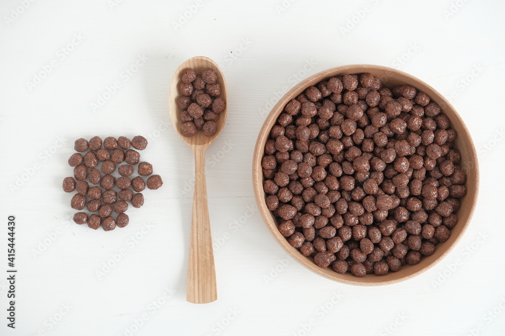 Chocolate corn balls in a wooden bowl and spoon scattered on a white background. Top view. Copy, empty space for text Chocolate corn balls in a wooden bowl and spoon scattered on a white background. Top view. Copy, empty space for text