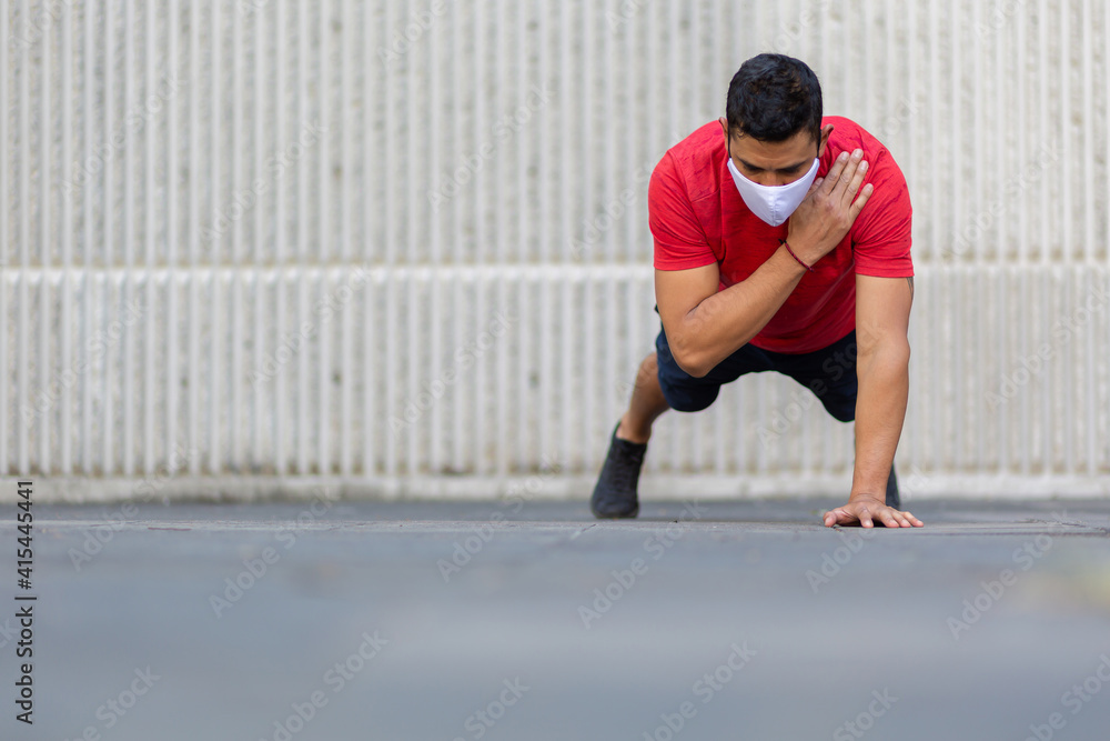 Mexican man doing push ups outdoors wearing a white face mask