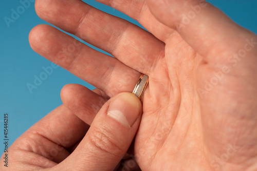 Man's hand touches gold wedding ring on finger on other hand, close