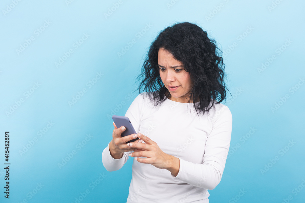 brunette girl looks surprised at her cell phone screen brunette girl looks surprised at her cell phone screen