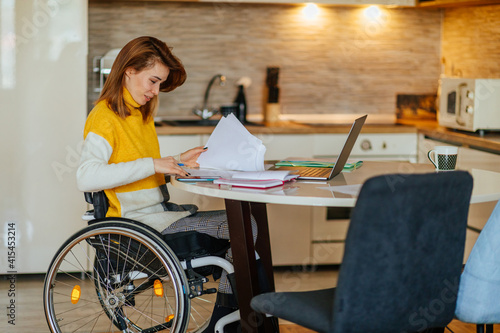 Obraz na plátne Woman sitting in her wheelchair while working at home