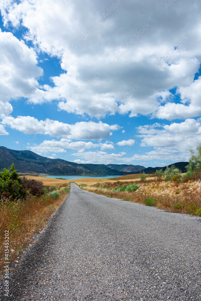 Road to the lake in the mountains with blue sky and clouds