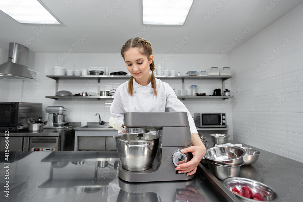 Pastry chef in the kitchen of the restaurant includes a mixer, food processor Pastry chef in the kitchen of the restaurant includes a mixer, food processor