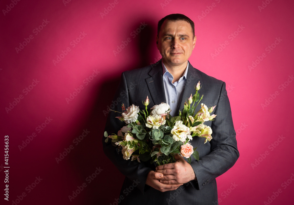 handsome businessman in a suit looks at the camera with a bouquet of flowers. handsome businessman in a suit looks at the camera with a bouquet of flowers.