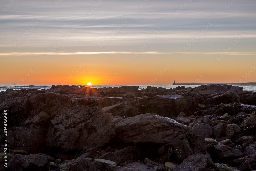 Sunrise on Tynemouth's Longsands beach as the sun appears on the horizon over the rocks Sunrise on Tynemouth's Longsands beach as the sun appears on the horizon over the rocks