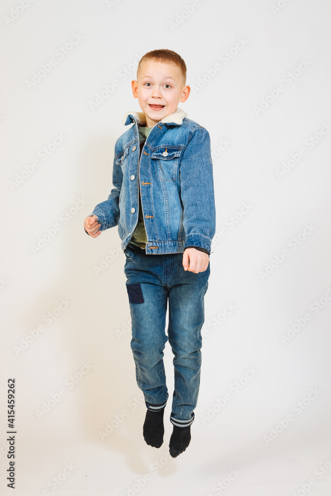 Blond boy in denim jacket jumps up. Child is happy. Feeling of excitement and joy in children Blond boy in denim jacket jumps up. Child is happy. Feeling of excitement and joy in children