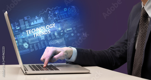 Businessman working on laptop with TECHNOLOGY TRENDS inscription, cyber technology concept