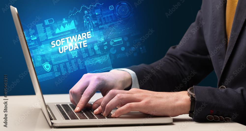 Businessman working on laptop with SOFTWARE UPDATE inscription, cyber technology concept Businessman working on laptop with SOFTWARE UPDATE inscription, cyber technology concept