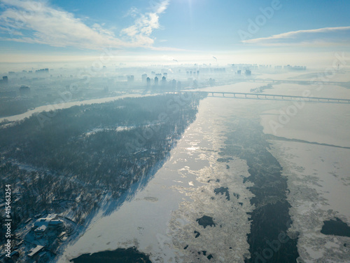 The frozen Dnieper river in Kiev in sunny weather. Aerial drone view. Winter sunny morning.