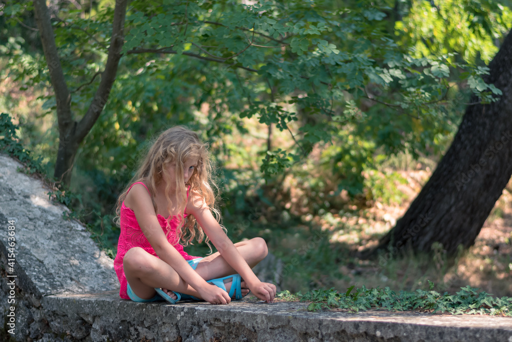 child with beautiful blond hair sitting in green park child with beautiful blond hair sitting in green park