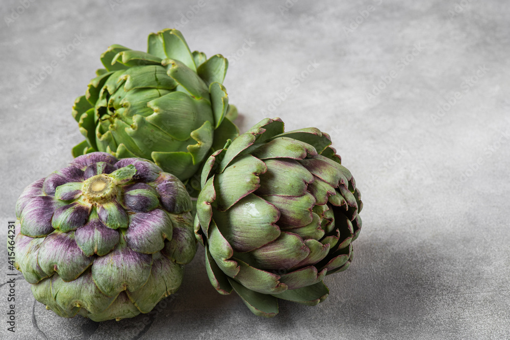 Fototapeta premium Fresh ripe artichokes flowers vegetable on gray background. Healthy vegetarian food