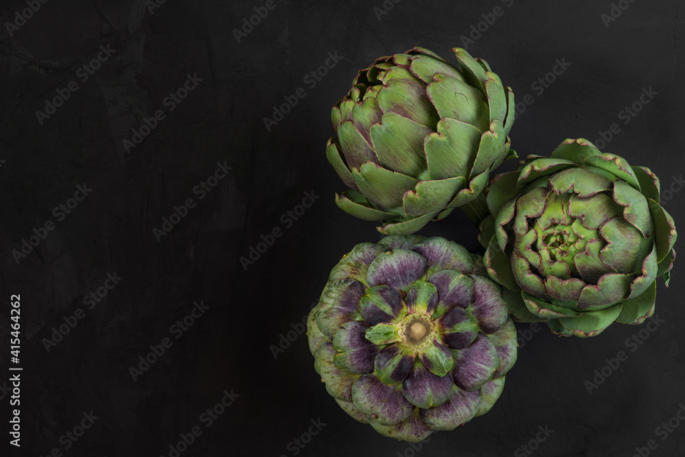 Fototapeta premium Fresh ripe artichokes flowers vegetable on black background. Healthy vegetarian food. top view with copy space