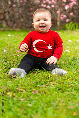 Portrait of happy little kid, cute baby toddler with Turkish flag t-shirt. Patriotic holiday. Adorable child celebrates national holidays. Blur background with copy space for text.