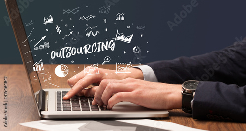Businessman working on laptop with OUTSOURCING inscription, modern business concept