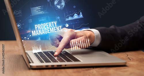 Businessman working on laptop with PROPERTY MANAGEMENT inscription, new business concept