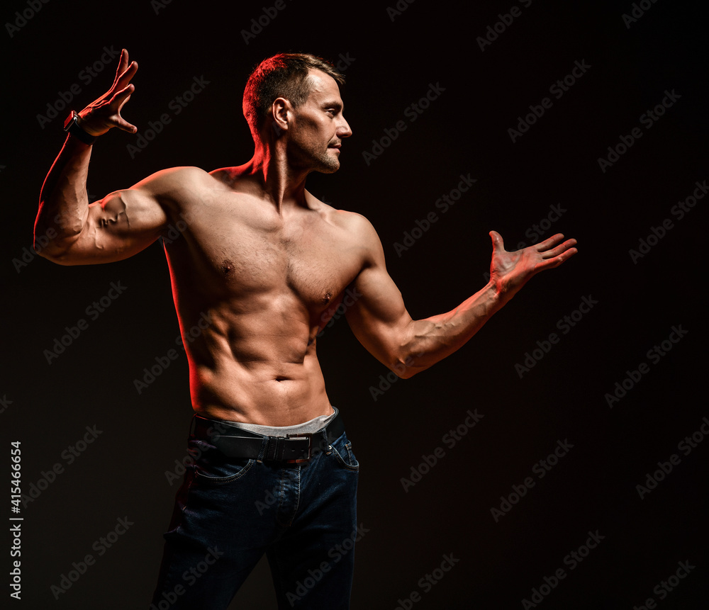 Handsome sexy man with athletic shirtless body showing muscle standing isolated on black background. Sport, bodybuilding motivation. Narcissism and masculinity. Dark studio shot copy space portrait Handsome sexy man with athletic shirtless body showing muscle standing isolated on black background. Sport, bodybuilding motivation. Narcissism and masculinity. Dark studio shot copy space portrait
