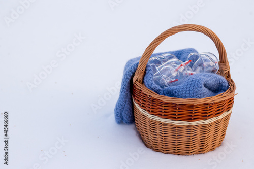 Jars for hijama in a basket in the snow. Wicker basket. Bloodletting according to the Sunnah. Vacuum therapy. medical and health concept. Winter and snow.