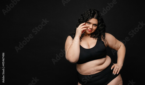 Plus size model in lingerie, fat sexy woman in underwear on black studio background, body positive concept, full length portrait. Girl model plus size talking on the phone