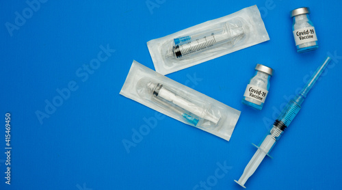 Top view, medical syringes and vaccine in ampoules from Covid 19 on a blue background. Protection during a pandemic.