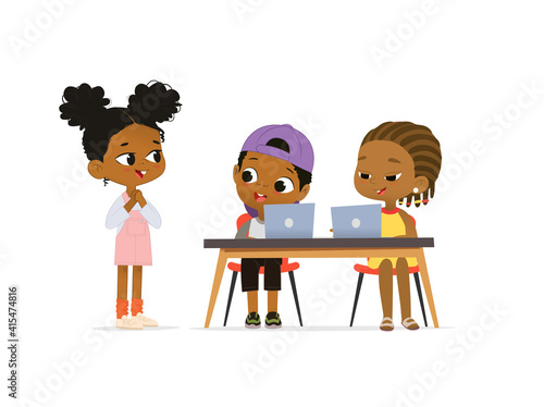 New pupil greeting classmates sitting at table. Happy African American children sitting at laptops and learning programming during school lesson
