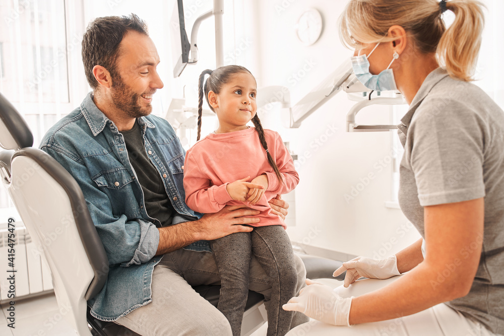 Obraz premium Girl and father talking with her pediatric stomatologist