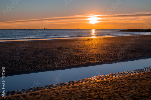 sunset at sea, sun on the same level with the sea and casual passers-by on the run