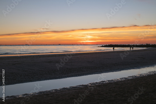 sunset at sea, sun on the same level with the sea and casual passers-by on the run