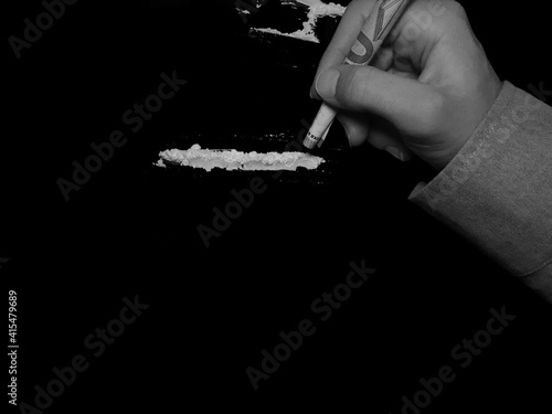 Businessman use 50 euro banknote to snorting cocaine drug powder lines on black table