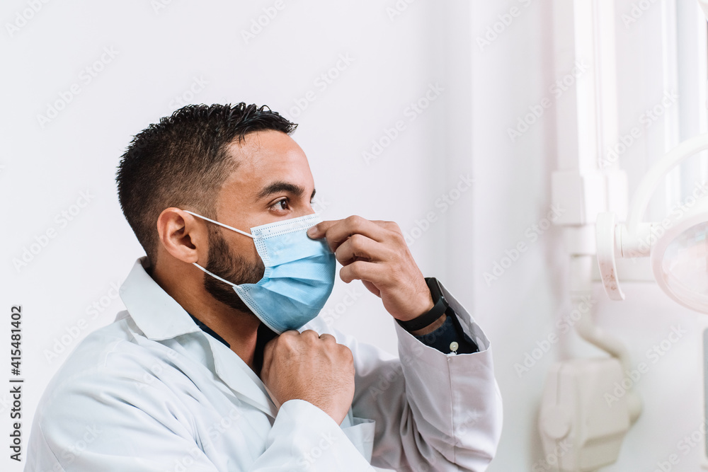 adult male doctor or dentist putting on or taking off a surgical mask. health and hygiene concept. corona virus and pandemic.