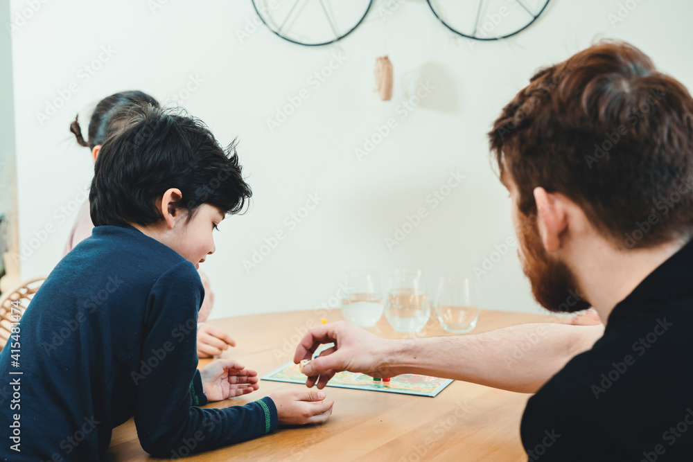 Multinational family sitting together at the table and playing with board game. Real life, diversity, digital detox and unplugging from technology Multinational family sitting together at the table and playing with board game. Real life, diversity, digital detox and unplugging from technology