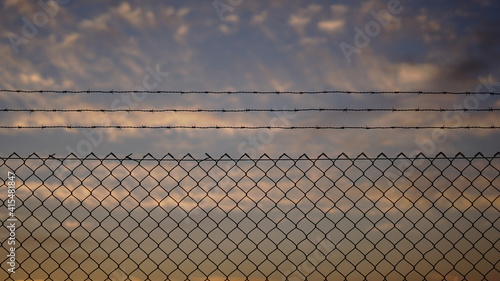 fence with barbed wire against sunset