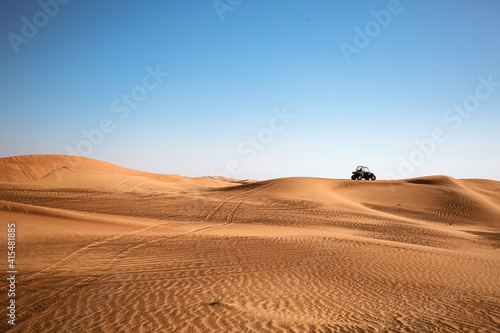 Desert sandy minimalistic landscape with one black buggy quad bike far and wheels traces, safari tour at wild nature