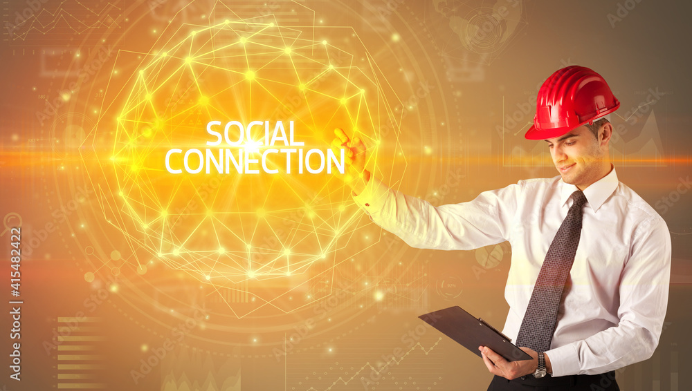 Handsome businessman with helmet drawing SOCIAL CONNECTION inscription, social construction concept Handsome businessman with helmet drawing SOCIAL CONNECTION inscription, social construction concept