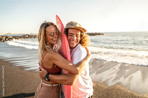 Photography Happy surfer couple with surfboard having fun on the beach, smiling, spending time together