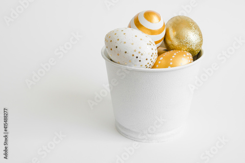 Easter golden decorated eggs in bucket on white background. Minimal easter concept. Happy Easter card with copy space for text