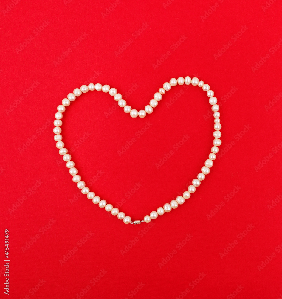 Heart of pearl beads on a red background