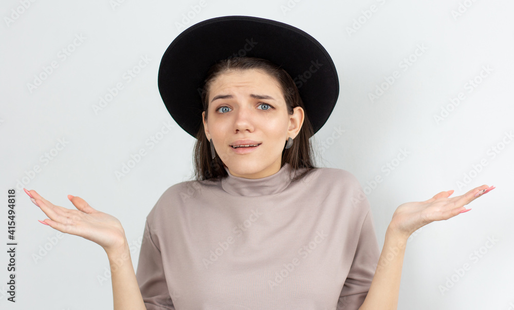 Portrait of a young woman shrugging shoulders over white background Portrait of a young woman shrugging shoulders over white background