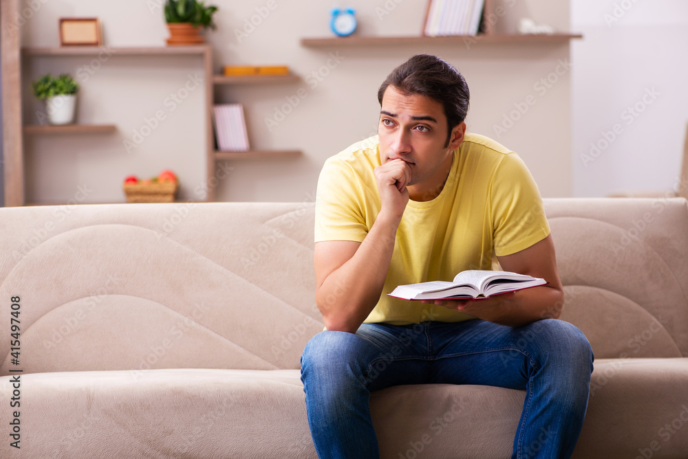 Young male student reading book at home Young male student reading book at home