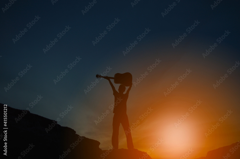 A silhouette of a man holding a guitar holding hands
