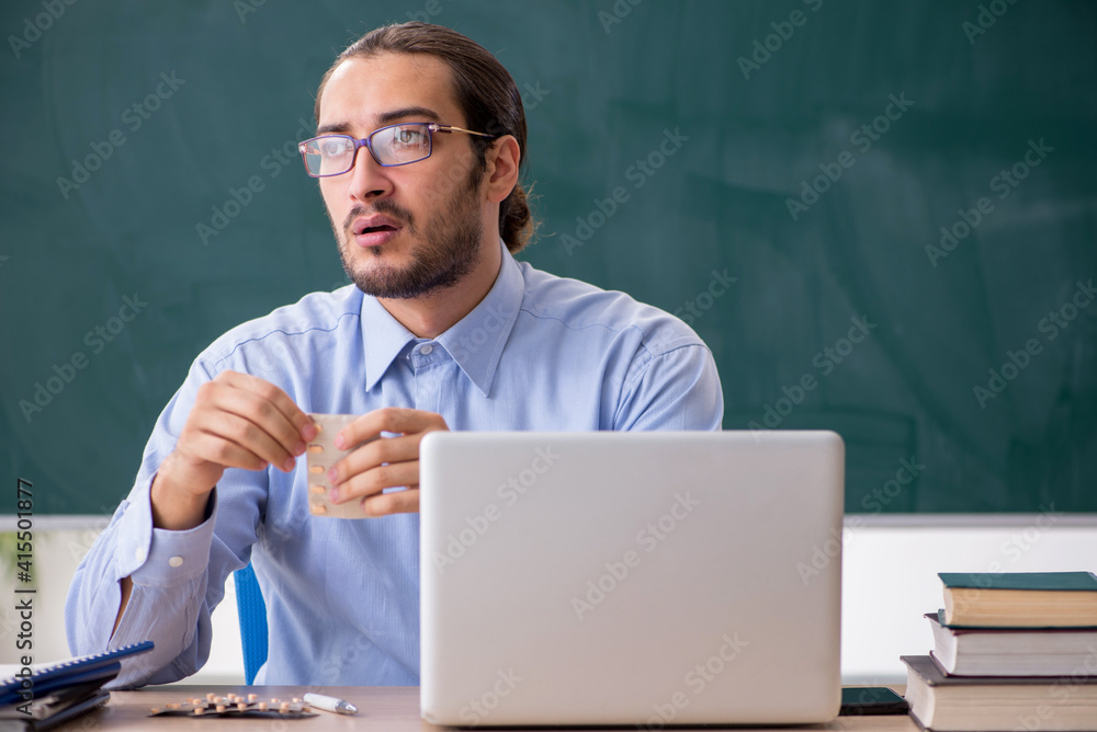 Young sick male teacher in the classroom Young sick male teacher in the classroom