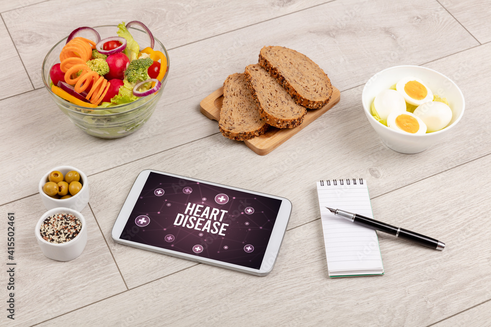 HEART DISEASE concept in tablet pc with healthy food around, top view HEART DISEASE concept in tablet pc with healthy food around, top view