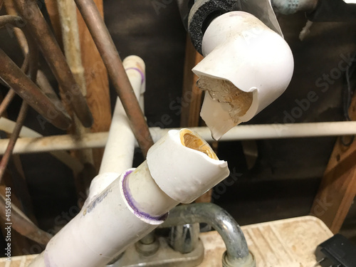 Busted plumbing PVC water pipe with ice frozen and water dripping