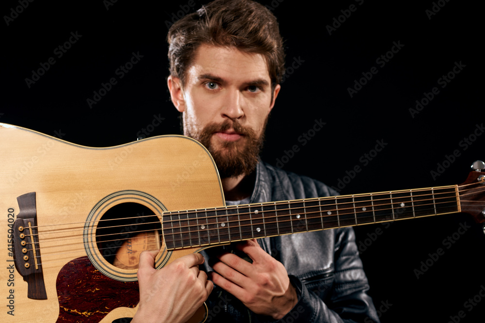Obraz premium A man with a guitar in his hands leather jacket music performance rock star modern style dark background