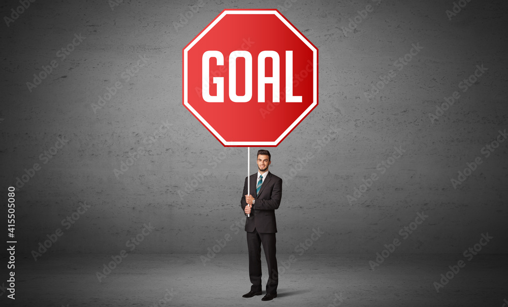 Young business person holding road sign with GOAL inscription, new rules concept Young business person holding road sign with GOAL inscription, new rules concept